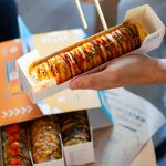 Caja de Sushi Box Sudoki Sushi & Fusion Barcelona para delivery, con rollos tempura, salsa teriyaki y topping crujiente, lista para disfrutar en casa.