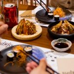 Pareja disfrutando del menú de mediodía en Sudoki Sushi & Fusion Barcelona, con gyozas, makis y refrescos en mesa del restaurante del Eixample.