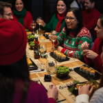 Grupo celebrando una cena de Navidad en Sudoki Sushi Barcelona con bandejas de sushi, edamame y copas en la mesa.
